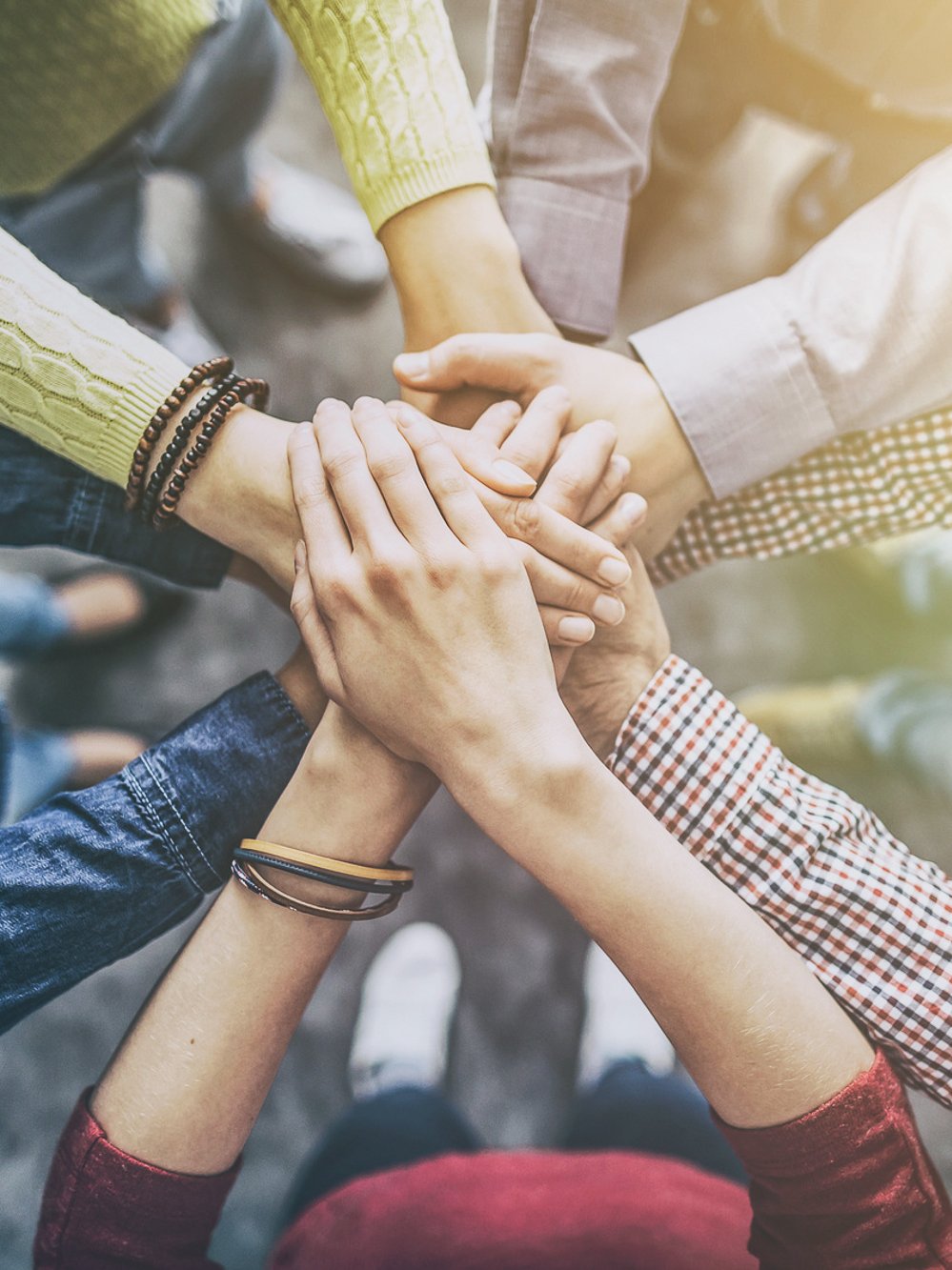 Teamwork: Mitarbeiter stehen im Kreis und legen Hände aufeinander