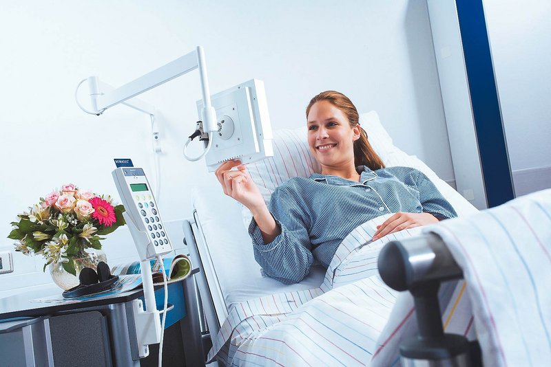 BEWATEC Unternehmensgeschichte | Patientin im Krankenhausbett bedient BEWATEC MediTec LCD TV